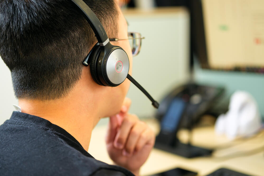 Technician wearing a headset, deep in thought at his desk